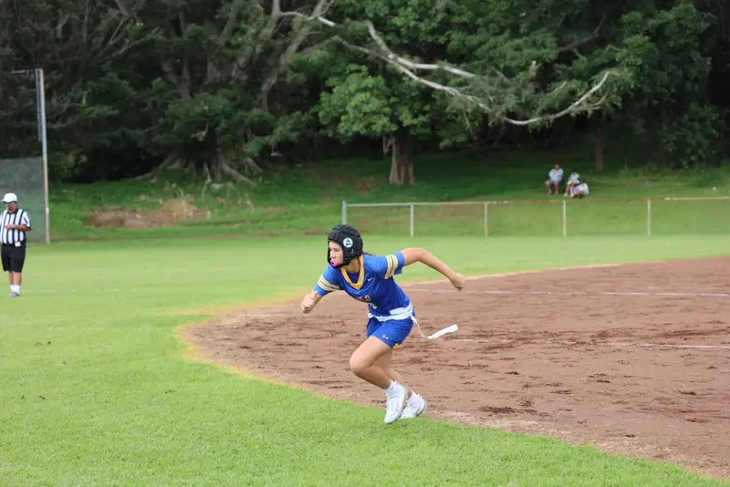 A young athlete sprints across a softball field.